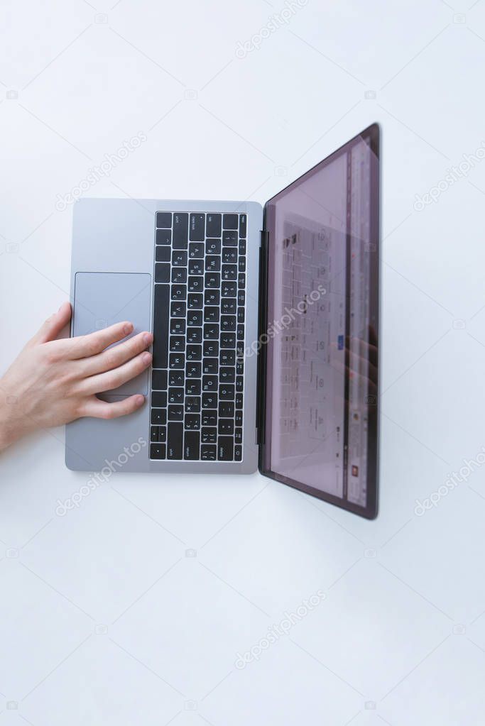 Man's hand works on a laptop on a white table top view. A man uses a touchpad. Workplace. Copyspace.
