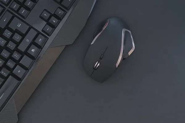 Black mouse, keyboard isolated on a dark background, top view. Flat lay gamer background. Workspace with a keyboard and mouse on a black background. Copyspace