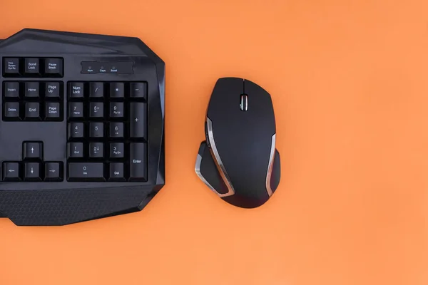オレンジ色の背景上にマウスとキーボードのワークスペースです Copyspace 黒マウス キーボードのオレンジ色の背景は 平面図上で分離します フラット横たわっていたゲーマーの背景 — ストック写真