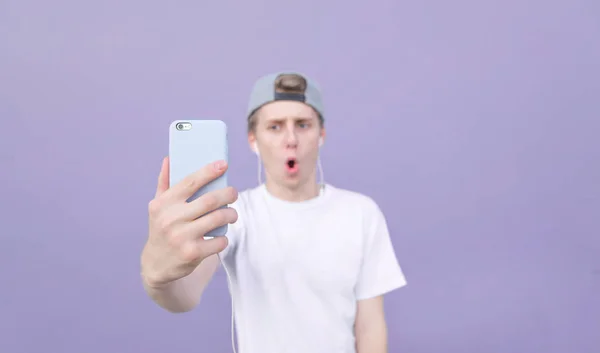 남자는 화이트 티셔츠 파스텔 보라색 배경에 Selfie 걸립니다 스마트폰에 — 스톡 사진