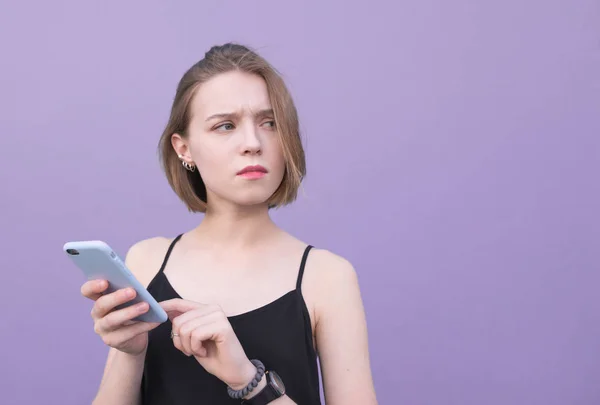 Привлекательная Девушка Использует Смартфон Фоне Фиолетовой Стены Смотрит Вне Поля — стоковое фото