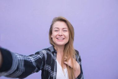 Mor bir arka plan üzerinde duran ve onun portre fotoğraf makinesini yapma bir kız portresi. Mutlu kız selfie bir parlak mor arka plan üzerine alır..