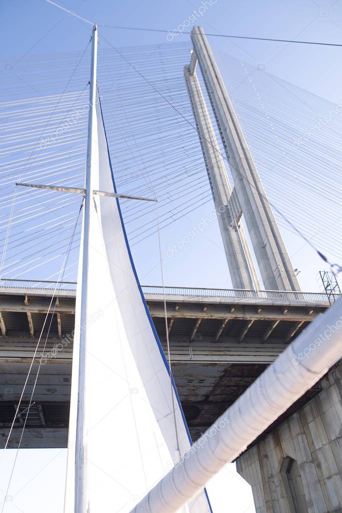 Sail yacht and bridge view from below. Sailing yacht floating under the bridge. Background
