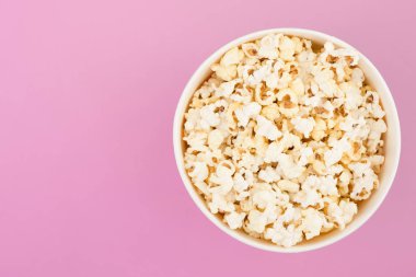 Pastel pembe arka plan, yukarıdan bir görünümü üzerinde patlamış mısır bir kağıt bardak içinde izole. Düz yatıyordu. Boşaltmak. Arka plan. Sinema kavramı