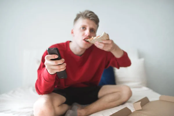 Jovem Uma Camisola Vermelha Senta Casa Cama Morde Pedaço Pizza — Fotografia de Stock