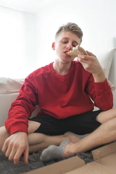 Jovem Atraente Uma Camisola Vermelha Senta Seu Quarto Chão Come — Fotografia de Stock