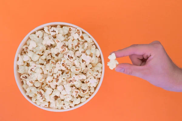 Männliche Hand Nimmt Ein Popcorn Aus Einem Pappbecher Auf Orangefarbenem — Stockfoto