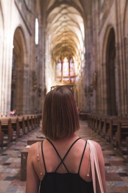 Kadın turist St. Vitus Katedrali, Prag ayakta elbise giymiş. Bir kız güzel bir tarihi kilise içinde ayakta portresi. Kız eski, tarihi Katolik tapınağın iç görünüyor.