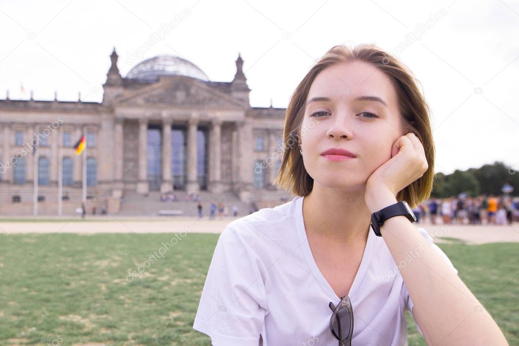 Portrait of an attractive young girl in a white T-shirt against the background of the Reichstag building in Berlin, Germany. Portrait of a tourist girl on the background of the Reichstag