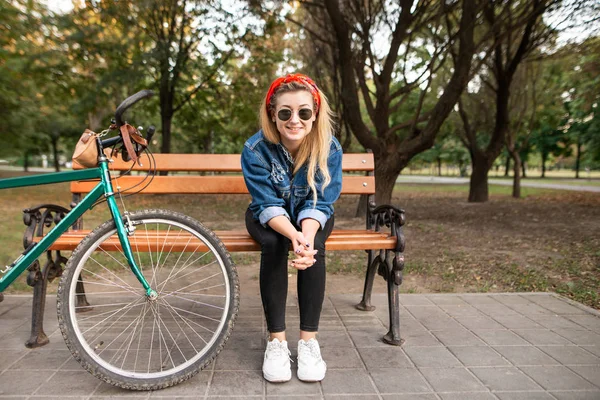 Menina Sorridente Roupas Elegantes Sentado Banco Parque Com Uma Bicicleta — Fotografia de Stock