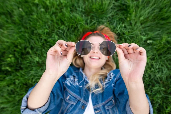 Menina Feliz Deitada Grama Verde Segurando Óculos Sol Suas Mãos — Fotografia de Stock