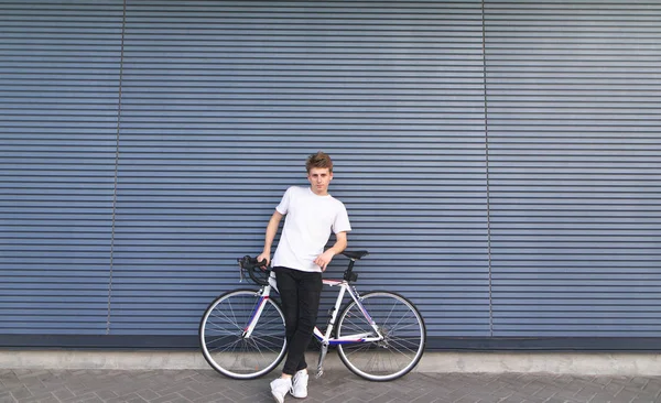 Jovem Elegante Fica Com Uma Bicicleta Estrada Branca Fundo Parede — Fotografia de Stock