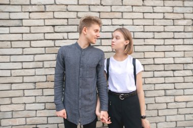 Bir tuğla duvar duvara karşı duran, birbirine bakarak ve gülümseyen güzel bir çift. Aşık bak.