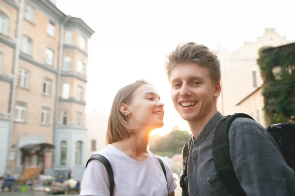 夕暮れ時 街を歩いて幸せな若いカップルのストリートの肖像 女の子が男の子を見て幸せなカップル 男の笑顔とカメラを見て — ストック写真