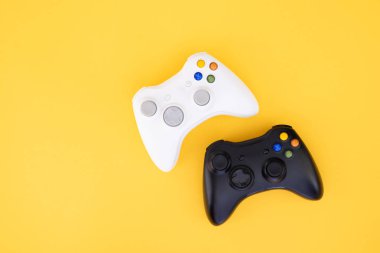 Beyaz ve siyah gamepad üzerinde sarı bir arka plan izole. Video oyunu yarışması. Sarı bir arka plan üzerinde siyah ve beyaz joystick. Oyun kavramı. Üstten görünüm. Düz yatıyordu