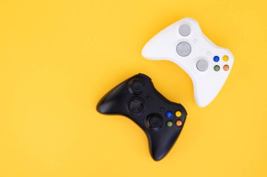 Beyaz ve siyah gamepad üzerinde sarı bir arka plan izole. Video oyunu yarışması. Sarı bir arka plan üzerinde siyah ve beyaz joystick. Oyun kavramı. Üstten görünüm. Düz yatıyordu