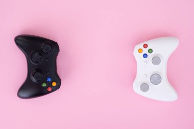 İki oyun çubukları, siyah pastel pembe bir arka plan üzerinde beyaz. Beyaz ve siyah gamepad bir pastel pembe izole. Oyun rekabet. Oyun kavramı. Boşaltmak