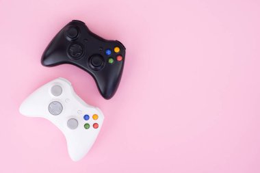 İki oyun çubukları, siyah pastel pembe bir arka plan üzerinde beyaz. Beyaz ve siyah gamepad bir pastel pembe izole. Oyun rekabet. Oyun kavramı. Boşaltmak