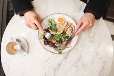 İştah açıcı bir salata etli adam elinde çatal ve bıçak ile yiyor, en iyi görünümü, kahve bir tablo kadar yakın. Bir restoranda yemek iş adamı. Öğle yemeği kavramı