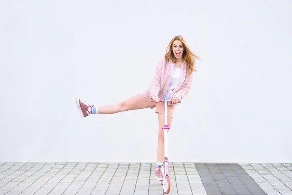 Забавная Девушка Розовой Одежде Едет Розовом Мотороллере Фоне Белой Стены — стоковое фото