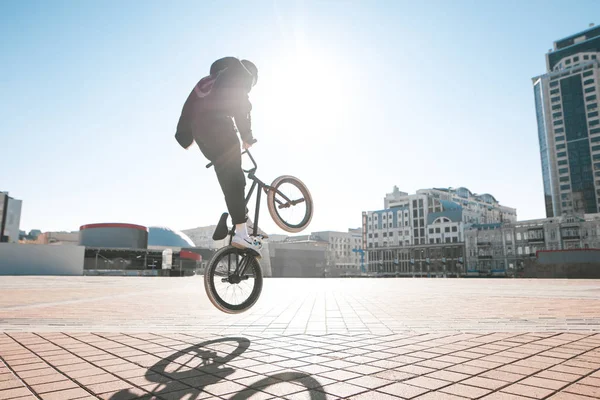 Bmx rider makes a trick on the street on a sunny day. Street bmx freestyle.