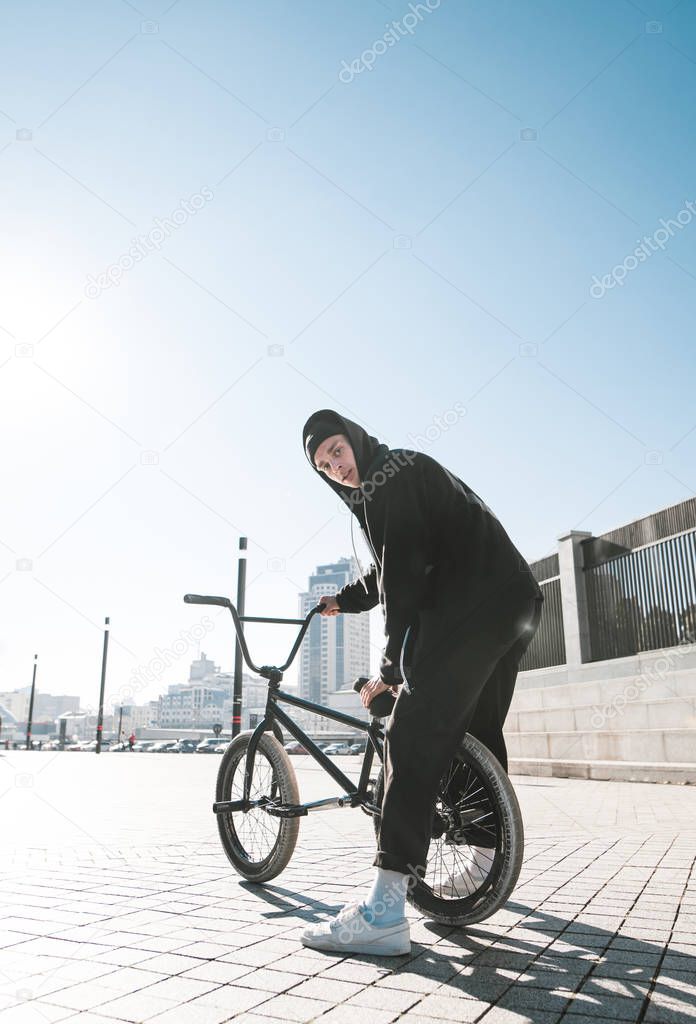 Portrait of cyclist sitting on bmx bikes, looking at camera at the background of a city on a sunny day. Bmx cyclist. Bmx concept