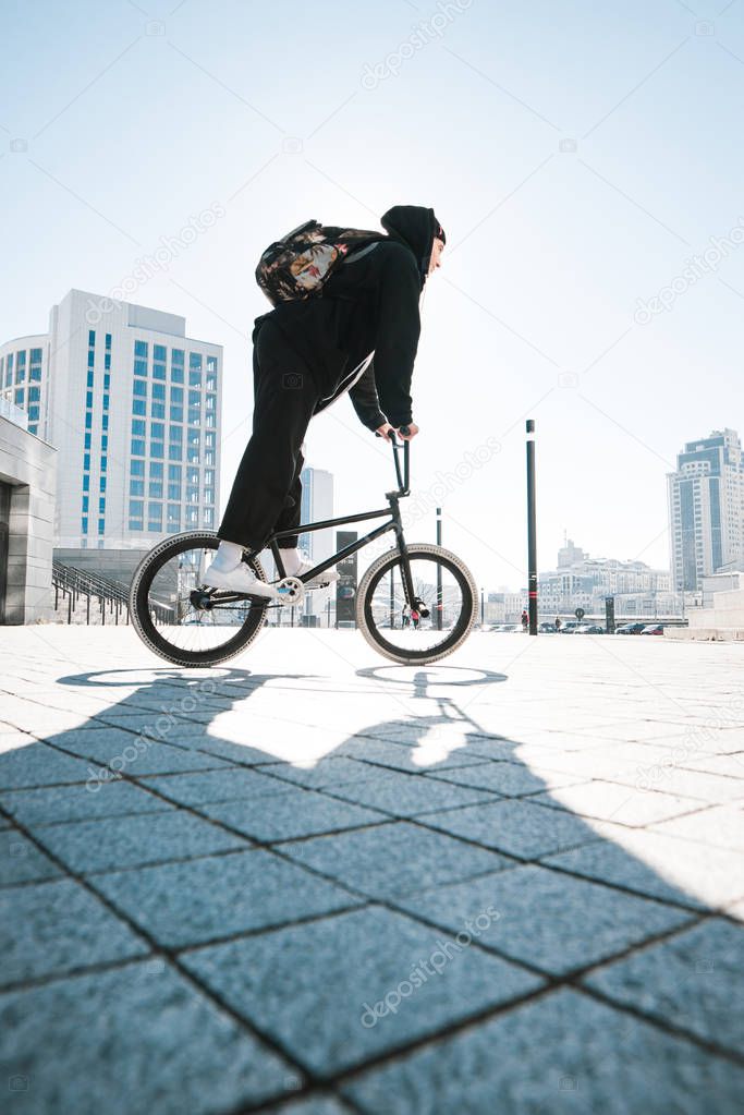 Young man riding a bmx bike on a sunny day. BMX cyclists ride a bike on the square. Bmx concept