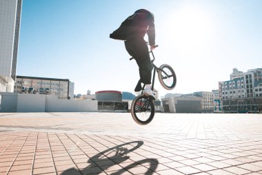 BMX sürücüsü olarak atlama şehir manzarası ve güneşin arka sokakta bir numara yapar. BMX kavramı. Sokak freestyle bmx üzerinde