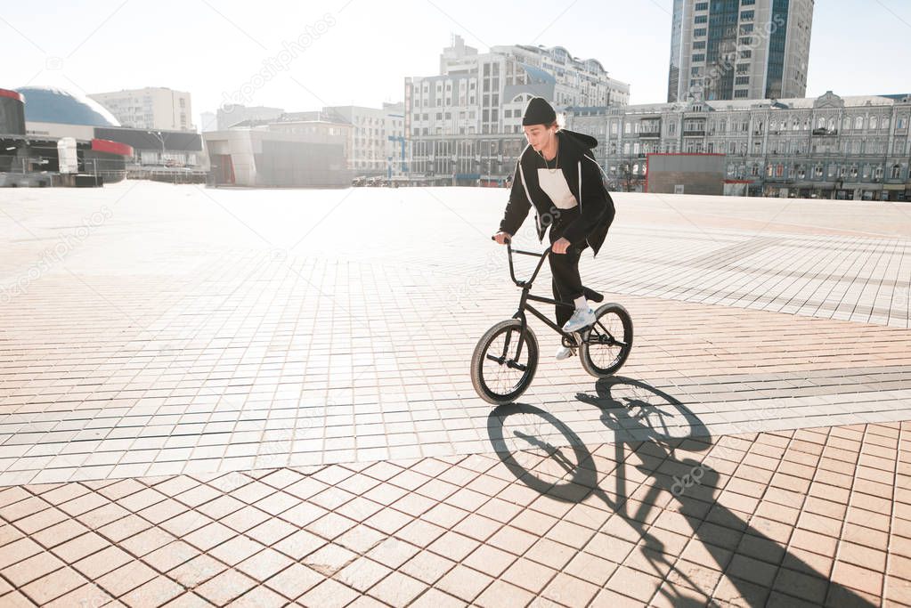 BMX cyclists ride a bike on the square on a sunny day. Young rider bmx bicycle walks through the city. BMX concept