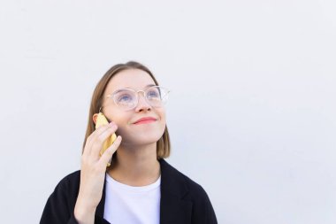 Mutlu öğrenci kız bardaklarda beyaz bir arka plan üzerinde duruyor ve telefonda konuşuyor. Telefonla arama gülümseyen bir iş kadın portresi. Boşaltmak