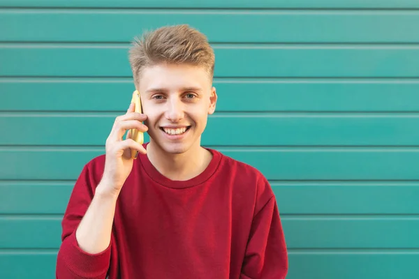 Sonriente Joven Habla Por Teléfono Mira Cámara Sonríe Sobre Fondo — Foto de Stock