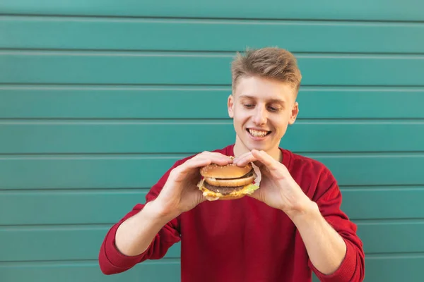대하여 손에서 음식을 배고픈 초상화는 잘생긴 남자의 햄버거와 샌드위치 청록색 — 스톡 사진
