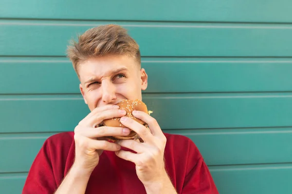 햄버거와 터키석 대하여 남자의 초상화를 닫습니다 배고픈 햄버거를 먹는다 패스트 — 스톡 사진