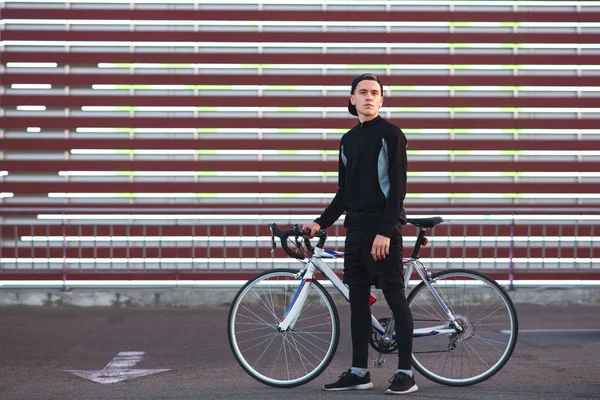 Aantrekkelijke Jonge Man Donkere Sportkleding Met Een Fiets Staat Gestreepte — Stockfoto