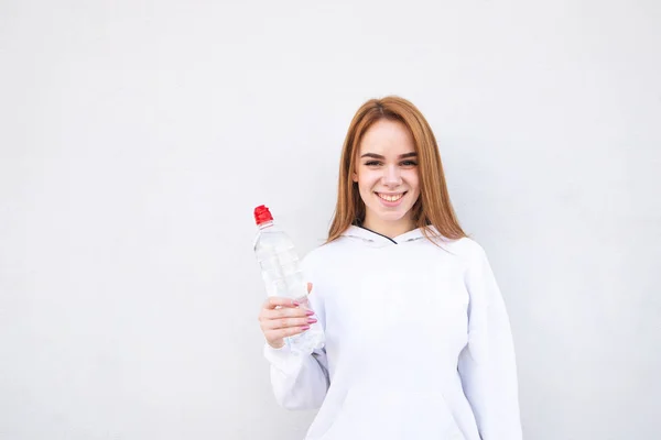 Šťastná Dívka Bílém Oblečení Lahví Vody Ruce Bílém Pozadí Úsměvy — Stock fotografie