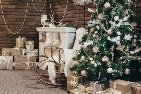Decor of the Christmas photo zone: a Christmas tree, rocking chair, fireplace and many gifts. Cozy New Year\'s photo area. Christmas concept
