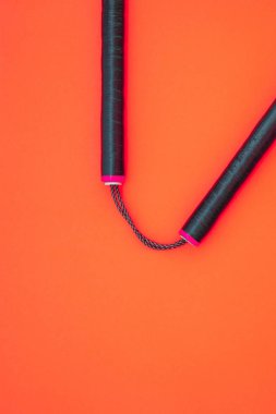 Kırmızı bir arka plan üzerinde siyah nunchaku eğitimi izole.