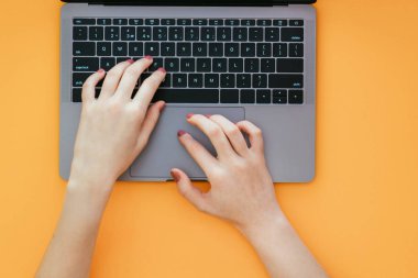 Kadınların elleri turuncu arka, üst laptop klavye metni yazın. Bir dizüstü bilgisayar üzerinde sarı bir arka plan izole iş