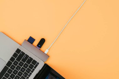 Modern dizüstü bilgisayar, Usb Type-C adaptörü flash ve turuncu arka plan üzerinde şarj ile. Teknoloji kavramı. Bağdaştırıcı için yeni standartlar.