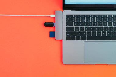 Modern dizüstü bilgisayar, Usb Type-C adaptörü flash ve kırmızı arka plan üzerinde şarj ile. Teknoloji kavramı. Boşaltmak. Bağdaştırıcı için yeni standartlar.