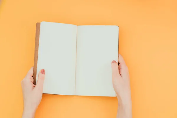 Hände Die Ein Geöffnetes Notizbuch Auf Orangefarbenem Hintergrund Halten Kopierraum — Stockfoto