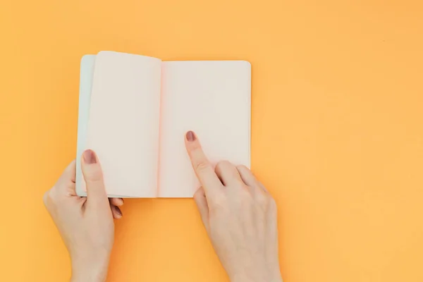Hände Halten Ein Geöffnetes Notizbuch Auf Orangefarbenem Hintergrund Und Zeigen — Stockfoto