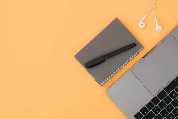 Portátil Moderno Auriculares Blancos Cuaderno Gris Con Bolígrafo Fondo Naranja — Foto de Stock