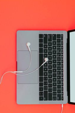 Modern metalik laptop ve beyaz kulaklık izole bir sarı arka plan ve boşaltmak, üstten görünüm. Düz yatıyordu. Müzik ile bir dizüstü bilgisayar üzerinde çalışmak.