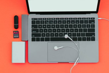 Defter ile Usb türü-C adaptörü, flash sürücüler, kulaklık ve güç izole kırmızı bir arka plan üzerinde banka. Modern bir dizüstü bilgisayar için gadgets.