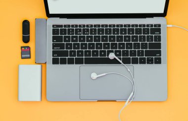 Defter ile Usb türü-C adaptörü, flash sürücüler, kulaklık ve güç izole sarı bir arka plan üzerinde banka. Modern bir dizüstü bilgisayar için gadgets.