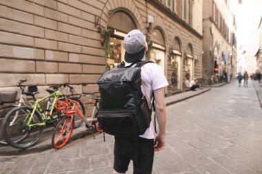 Genç Turizm büyük bir sırt çantası ile İtalya sokaklarında anlamına gelir ve örnek alıyor. Genç adam büyük bir sırt çantası ile Avrupa'ya seyahat