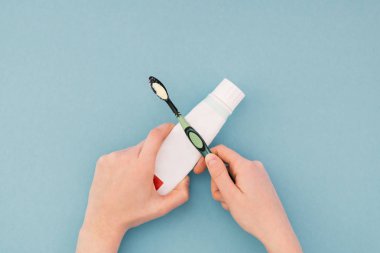 Kadın bir diş macunu diş fırçasını mavi arka plan, yukarıdan bir görünümü üzerinde tutar. Eller yakın çekim. İzole. Düz yatıyordu