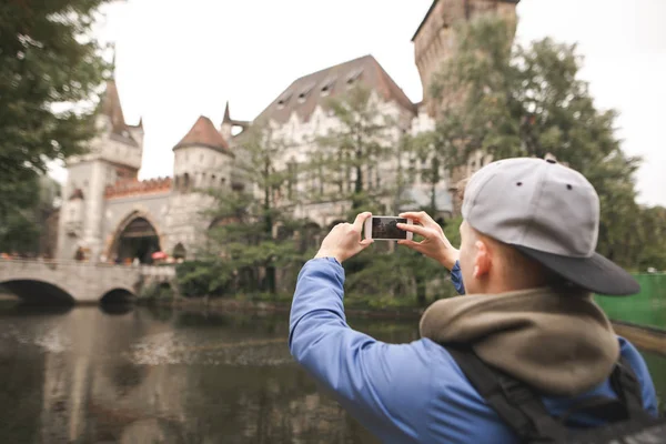 Tourist photographed the historic castle. Young tourist in a cap takes a photo on the smartphone Vajdahunyad Castle, also known as Dracula\'s castle. Budapest, Hungary