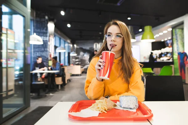 튀김과 햄버거와 컵에서의 트레이 패스트 레스토랑에 안경에 매력적인 식당에 앉아서 — 스톡 사진
